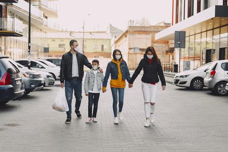 Familj med munskydd på är ute på promenad i stadsmiljö